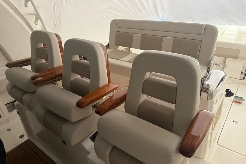 Slide: The Image of Luxury seating on 2024 Boston Whaler 420 Outrage boat, featuring plush cushions and wooden armrests. - 23