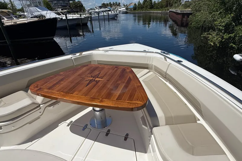 Slide: The Image of 2024 Boston Whaler 420 Outrage boat with elegant wooden table and seating area. - 73