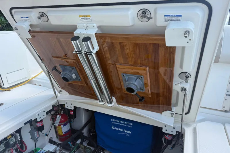 Slide: The Image of 2024 Boston Whaler 420 Outrage engine compartment with wooden panel and safety equipment. - 56