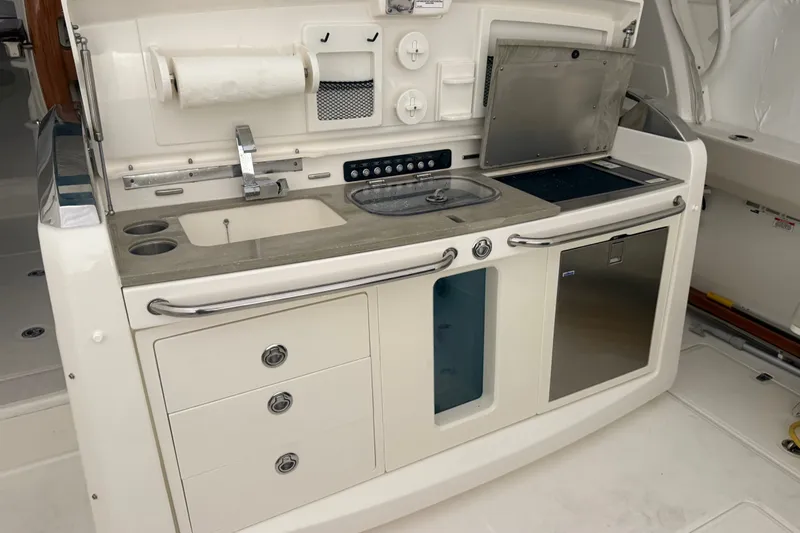 Slide: The Image of 2024 Boston Whaler 420 Outrage boat kitchen with sink, storage, and stainless steel appliances. - 21