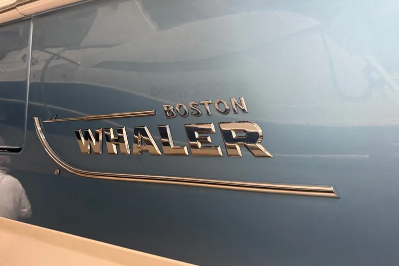 Slide: The Image of 2024 Boston Whaler 420 Outrage logo on a sleek blue hull. - 32