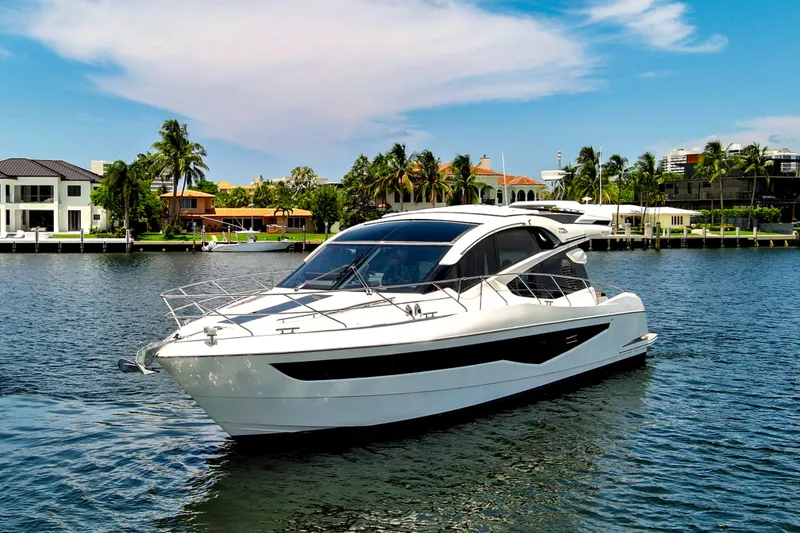 The Image of 2017 Galeon 560 Sky yacht cruising on a sunny waterfront with palm trees. - 0
