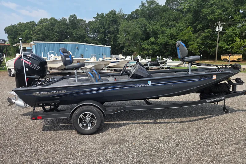 Slide: The Image of 2022 Ranger RT188 fishing boat on trailer, parked outdoors with trees in background. - 1