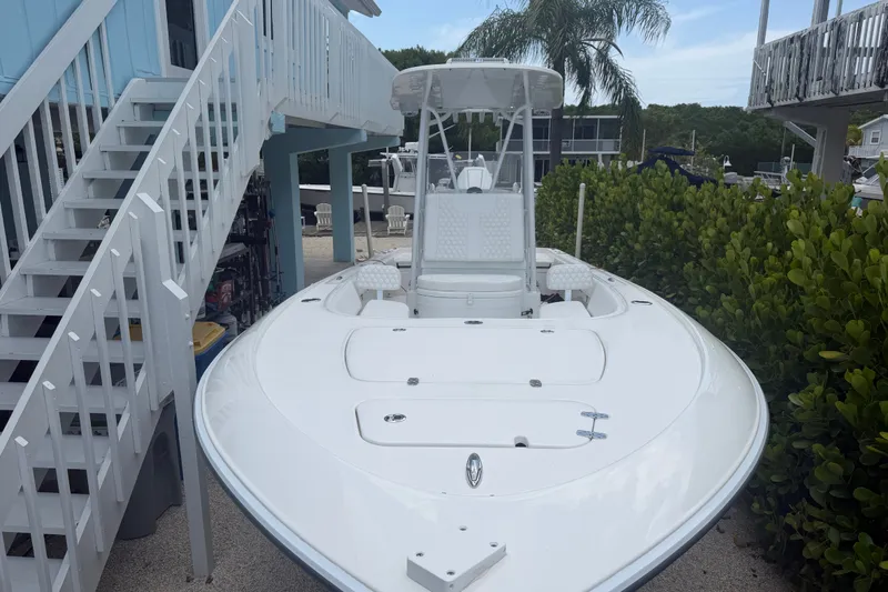 Slide: The Image of 2024 Contender 25 Bay boat docked near a house with lush greenery. - 30