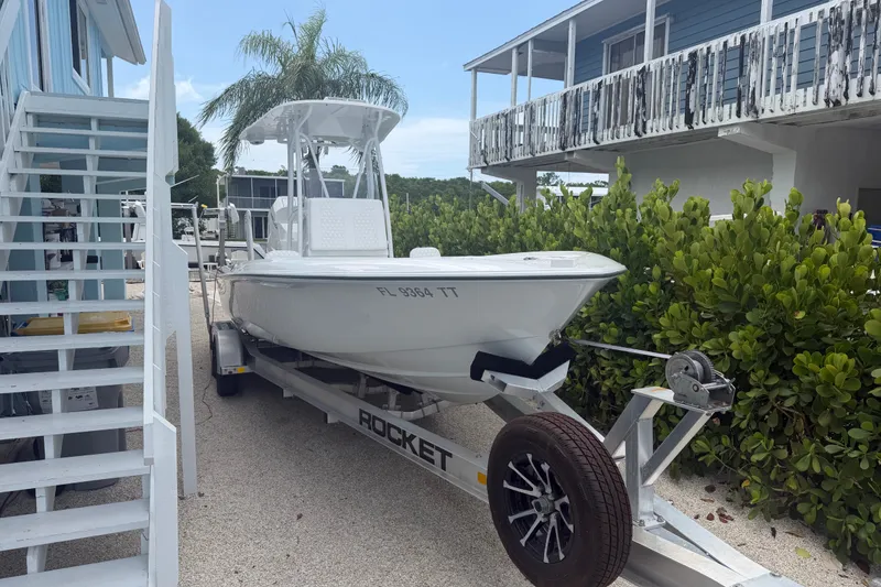 The Image of 2024 Contender 25 Bay boat on trailer beside a coastal house. - 27