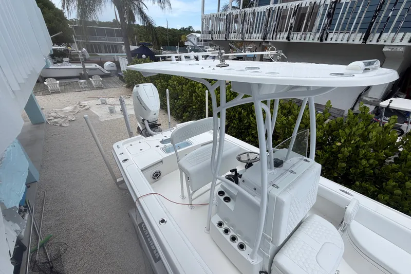 Slide: The Image of 2024 Contender 25 Bay boat with T-top and outboard motor in a marina setting. - 33