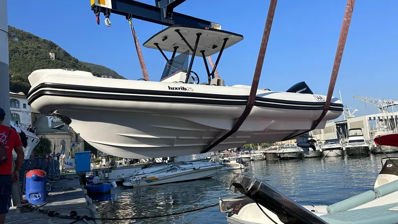 Slide: The Image of Aqvaboats Luxrib 25, 2025 model, being lifted at a marina. - 11