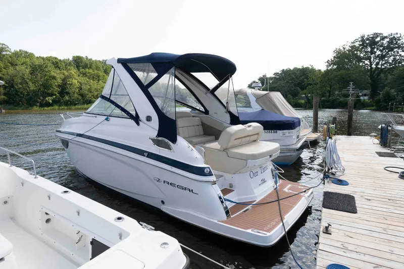 Slide: The Image of 2020 Regal 2860 Window Express boat docked by a wooden pier on a calm lake. - 1