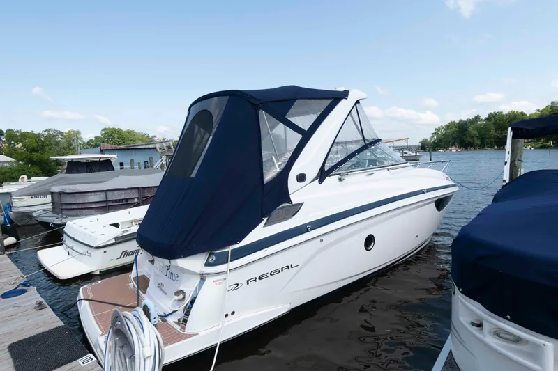 Slide: The Image of 2020 Regal 2860 Window Express boat docked at marina, featuring sleek design and blue canopy. - 2