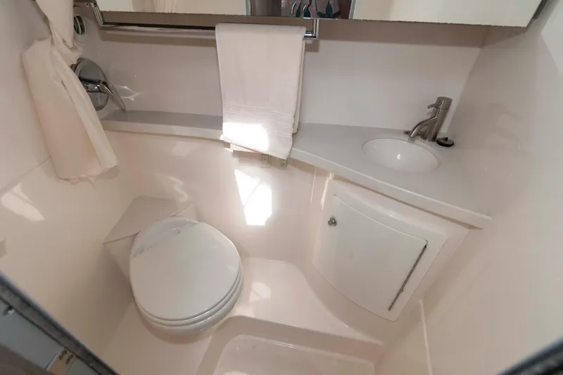 Slide: The Image of 2020 Regal 2860 Window Express boat bathroom with compact design, featuring toilet, sink, and storage. - 16