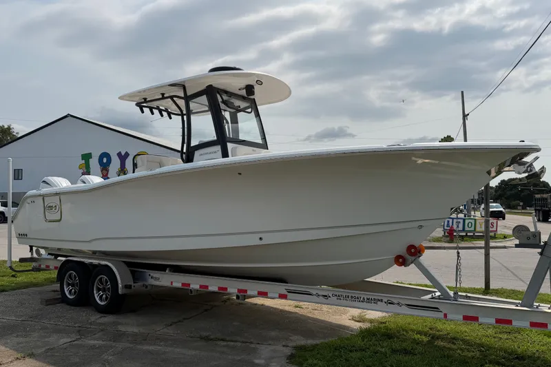 Slide: The Image of 2024 Sea Hunt Ultra 275 SE boat on trailer, parked outdoors under cloudy sky. - 13