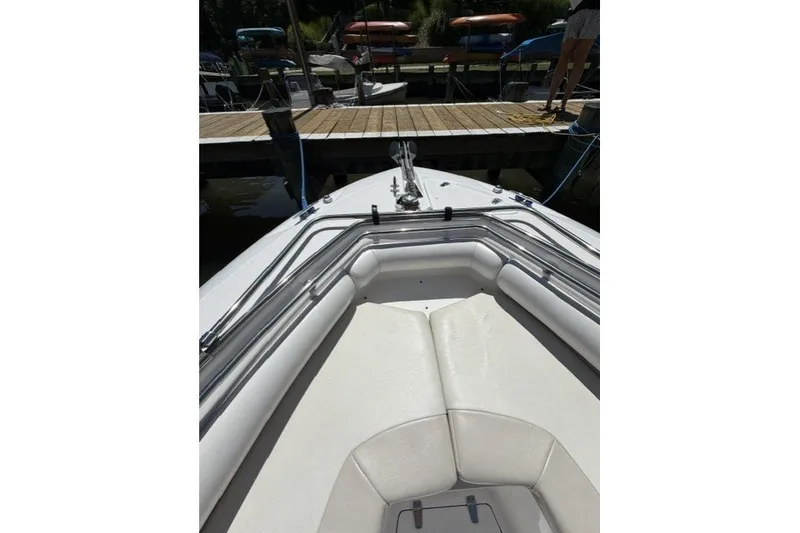 Slide: The Image of 2004 Boston Whaler 270 Outrage boat docked, featuring cushioned seating and stainless steel railings. - 5