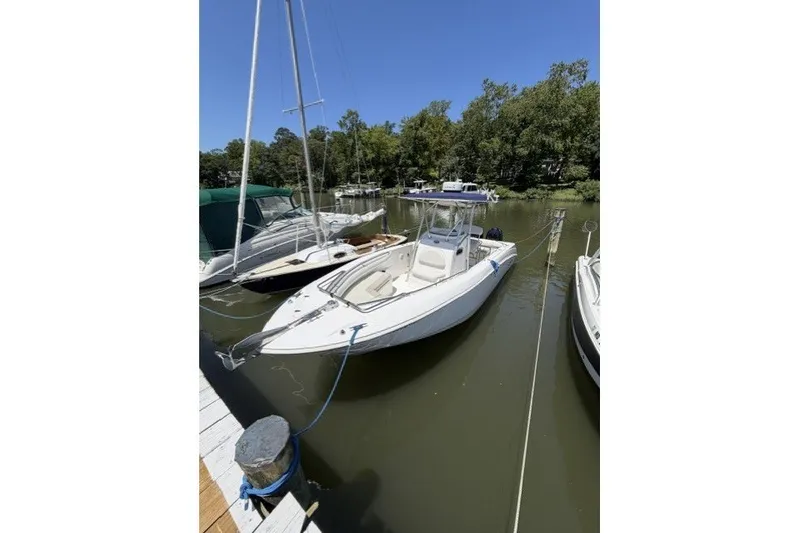 Slide: The Image of 2004 Boston Whaler 270 Outrage boat docked in a serene marina setting. - 1