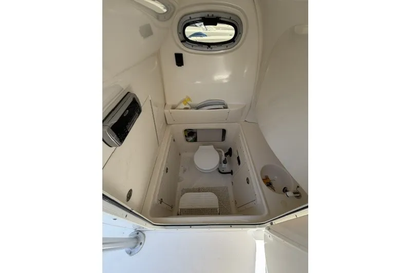 Slide: The Image of Interior of 2004 Boston Whaler 270 Outrage boat, featuring a compact marine toilet. - 16