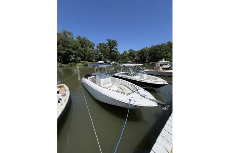 Slide: The Image of 2004 Boston Whaler 270 Outrage boat docked on a calm river under clear blue skies. - 2