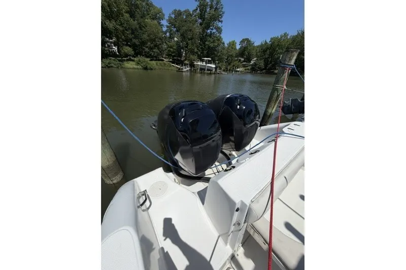 Slide: The Image of 2004 Boston Whaler 270 Outrage with dual engines docked on a serene river. - 15