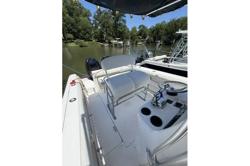 Slide: The Image of 2004 Boston Whaler 270 Outrage boat interior with seating and steering console on a calm river. - 9