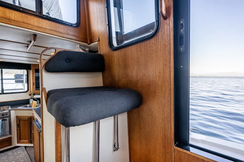 Slide: The Image of Interior of a 2000 Nordic Tug 32 boat with wooden finishes and a cushioned seat. - 33