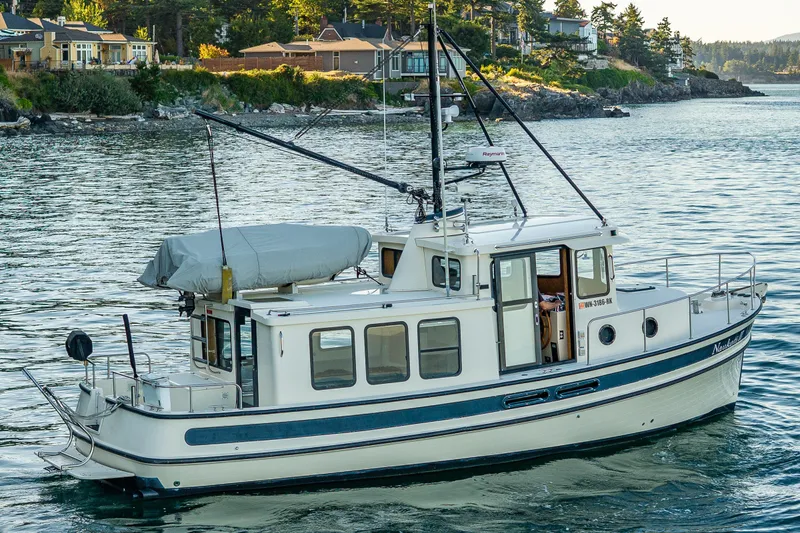 Slide: The Image of Nordic Tug 32, 2000 model, cruising near scenic shoreline with houses in the background. - 15