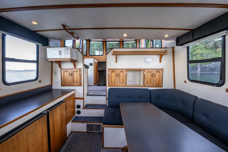 Slide: The Image of Interior of a 2000 Nordic Tug 32, featuring a cozy dining area and wooden cabinetry. - 24