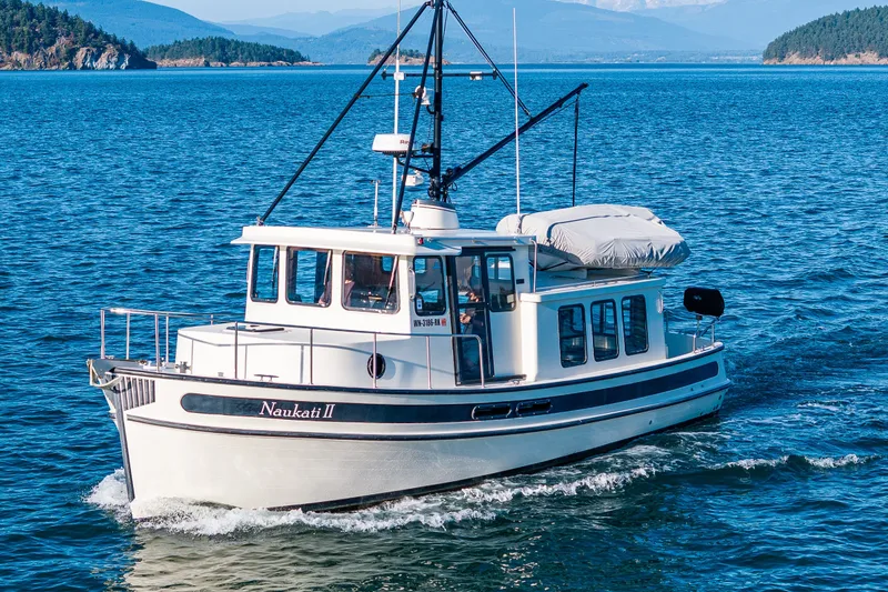 Slide: The Image of 2000 Nordic Tug 32 cruising on blue waters with scenic island backdrop. - 7