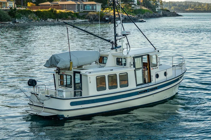 Slide: The Image of Nordic Tug 32 (2000) cruising on a scenic waterway near coastal homes. - 16