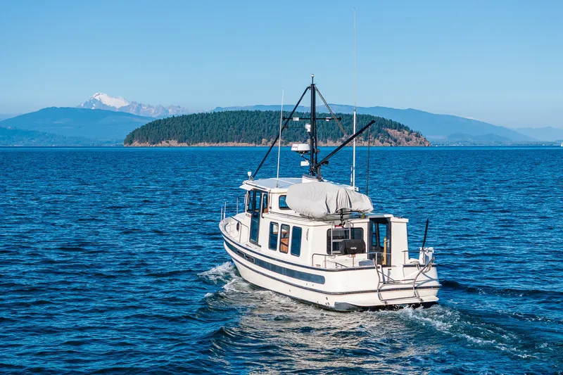 Slide: The Image of Nordic Tug 32 (2000) cruising on blue waters with scenic island backdrop. - 3