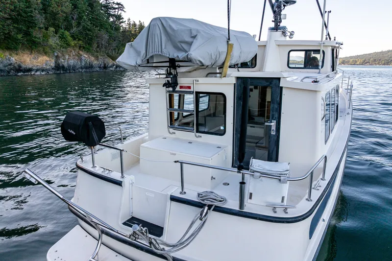 Slide: The Image of 2000 Nordic Tug 32 boat on calm water near forested shoreline. - 17