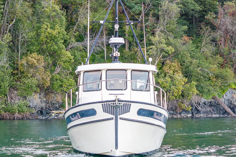 Slide: The Image of Nordic Tug 32 (2000) cruising on a serene lake with lush forest backdrop. - 13