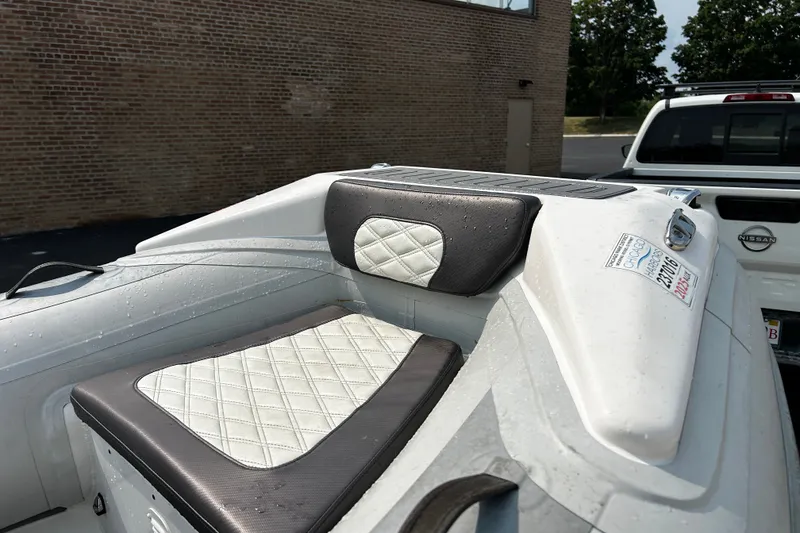 Slide: The Image of 2021 Highfield Sport 330 boat with cushioned seating, parked near a brick wall. - 13