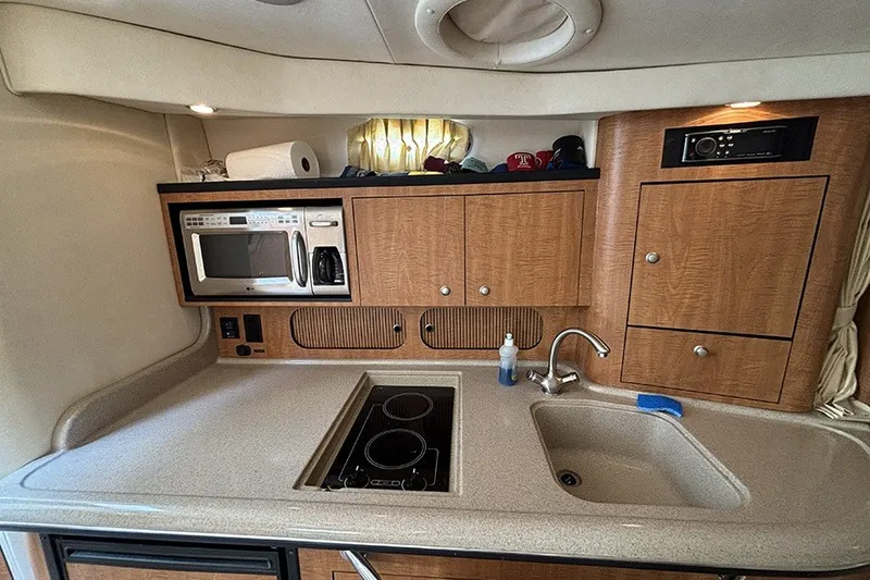 Slide: The Image of 2006 Sea Ray 340 Sundancer galley with microwave, stove, sink, and wooden cabinetry. - 24