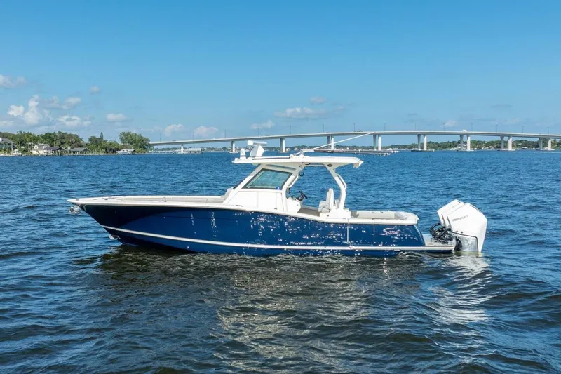 Slide: The Image of 2023 Scout 355 LXF boat on water with bridge in background. - 1