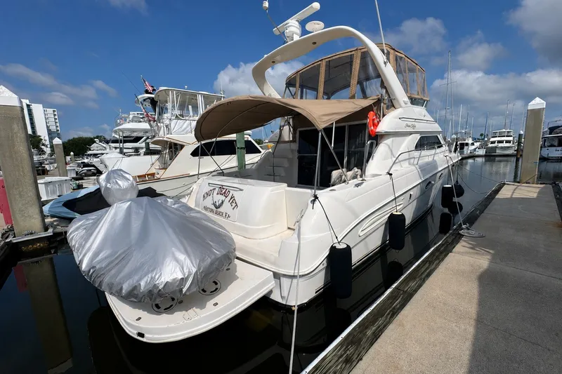 Slide: The Image of 2001 Sea Ray 450 Express Bridge yacht docked at marina under clear sky. - 2