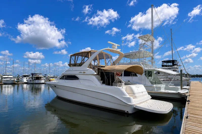 The Image of 2001 Sea Ray 450 Express Bridge yacht docked at marina under blue sky. - 0