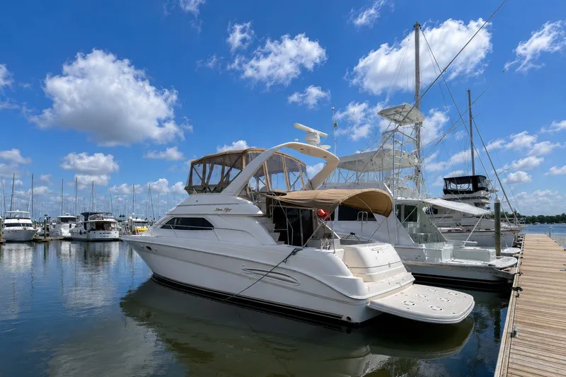 The Image of 2001 Sea Ray 450 Express Bridge yacht docked at marina under blue sky. - 0