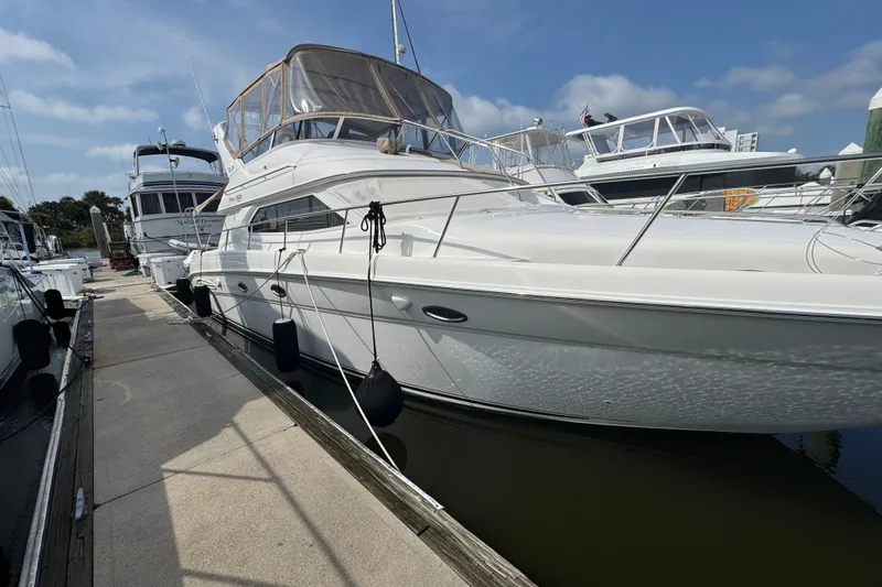 Slide: The Image of 2001 Sea Ray 450 Express Bridge yacht docked at marina under clear sky. - 1