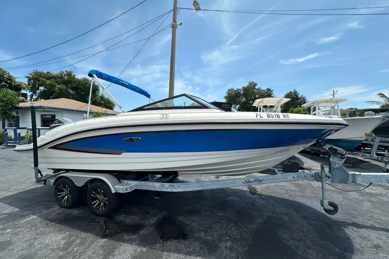 The Image of 2016 Sea Ray SPX 210 Outboard boat on trailer, blue and white design, parked outdoors. - 0