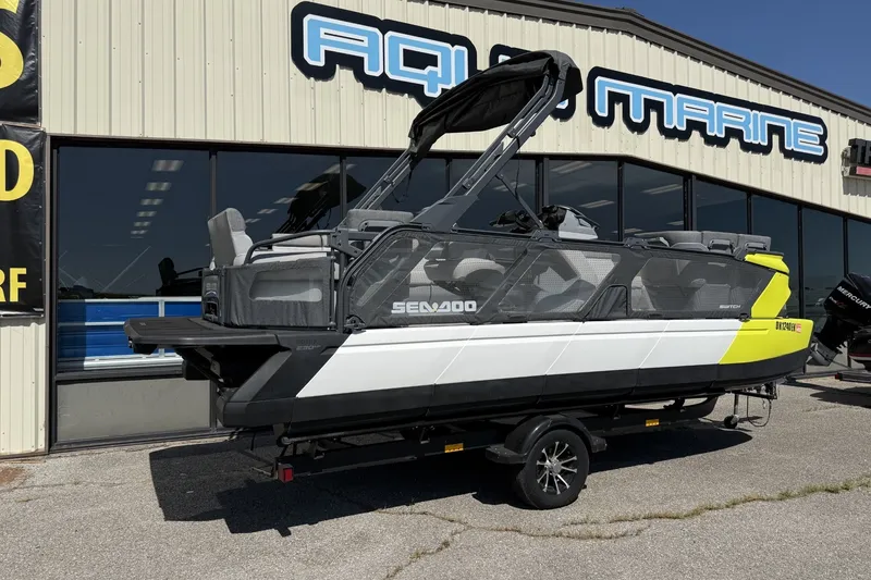 Slide: The Image of 2024 Sea-Doo Switch Cruise 21 pontoon boat displayed outside Aqua Marine dealership. - 1