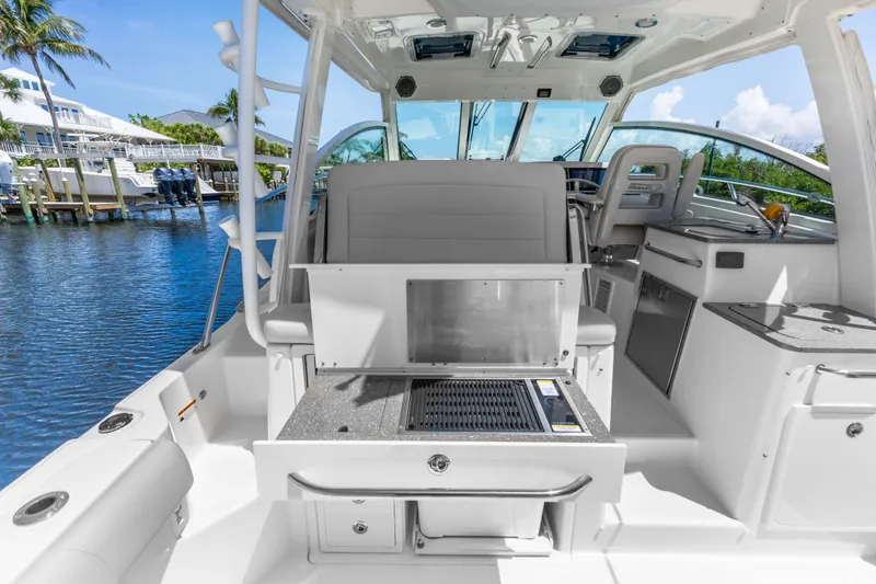 Slide: The Image of 2018 Boston Whaler 345 Conquest boat interior with seating and grill, docked by the water. - 22