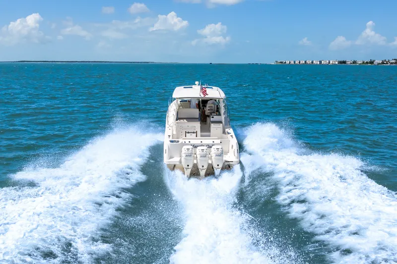 Slide: The Image of A 2018 Boston Whaler 345 Conquest speeds across the blue sea, with a flag at the stern. - 3