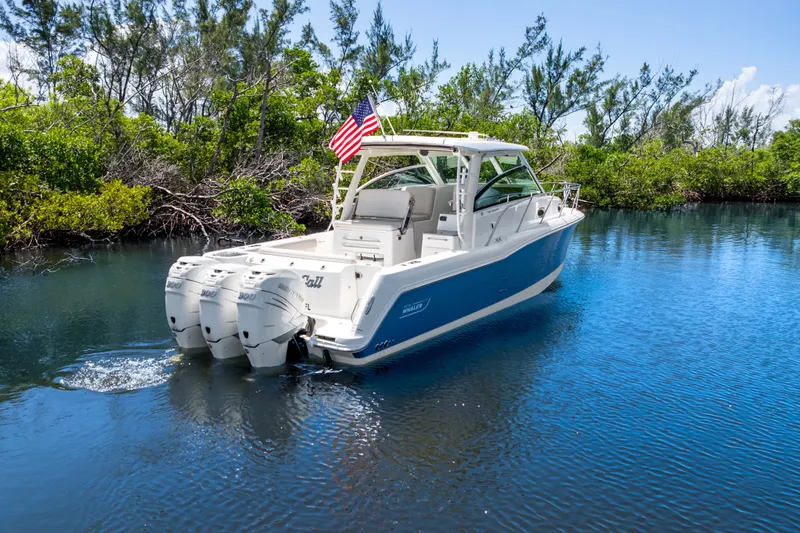 Slide: The Image of 2018 Boston Whaler 345 Conquest boat cruising in a serene, tree-lined waterway. - 8