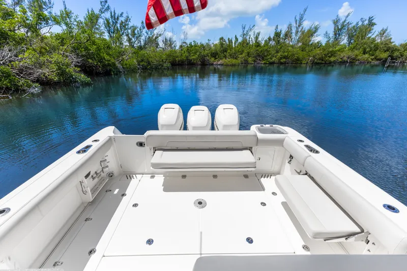 Slide: The Image of 2018 Boston Whaler 345 Conquest boat with spacious deck, scenic water view, and American flag. - 27