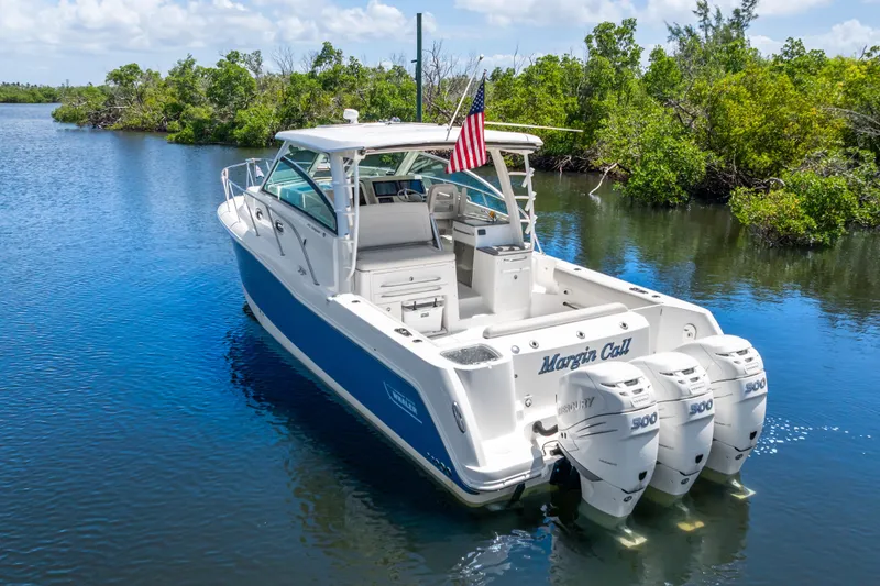 Slide: The Image of 2018 Boston Whaler 345 Conquest boat with triple Mercury engines on a serene waterway. - 6