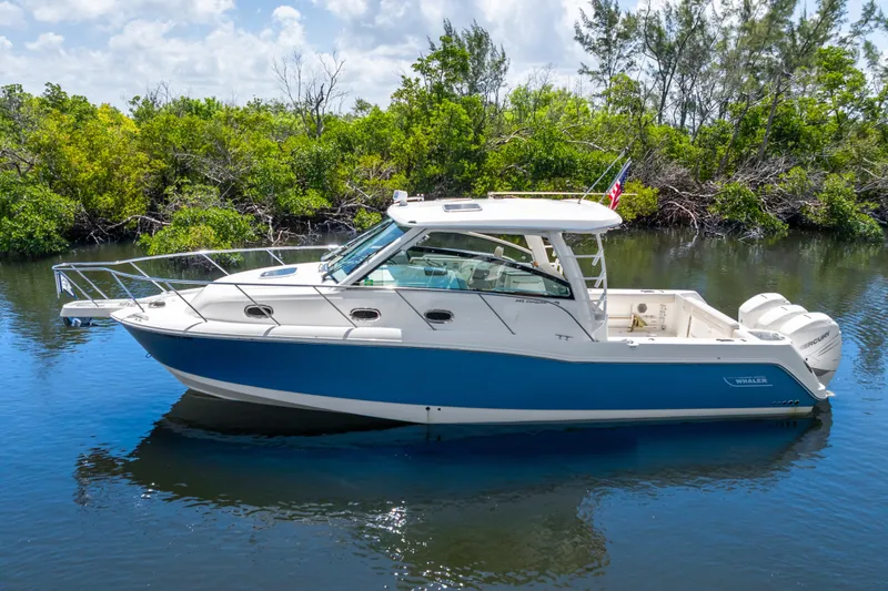 The Image of 2018 Boston Whaler 345 Conquest boat on calm water, surrounded by lush greenery. - 0