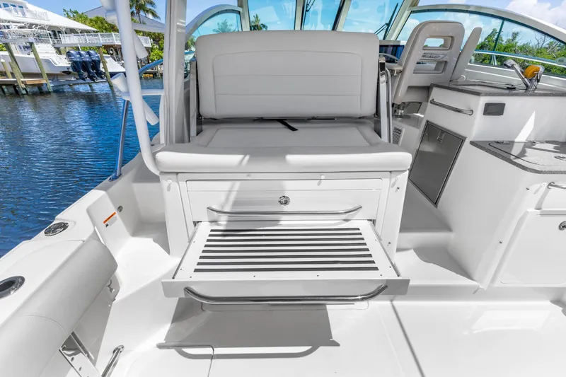Slide: The Image of 2018 Boston Whaler 345 Conquest boat interior with seating and storage, docked by the water. - 23