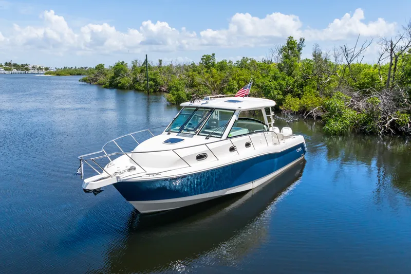 Slide: The Image of 2018 Boston Whaler 345 Conquest boat on a serene waterway with lush greenery. - 11