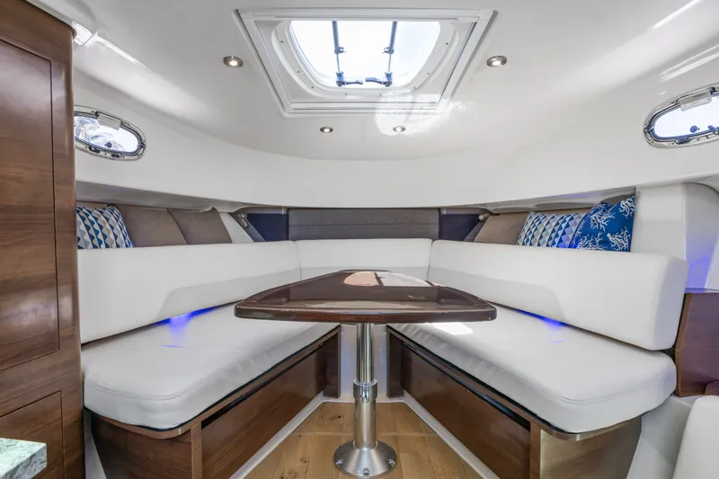 Slide: The Image of 2018 Boston Whaler 345 Conquest cabin interior with white seating and wooden table. - 37