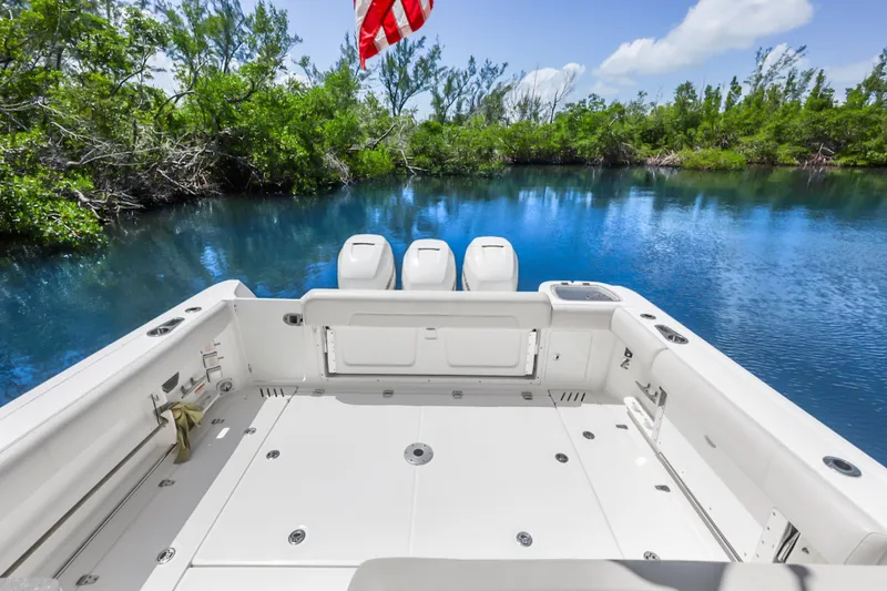 Slide: The Image of 2018 Boston Whaler 345 Conquest boat on serene water with lush greenery backdrop. - 18
