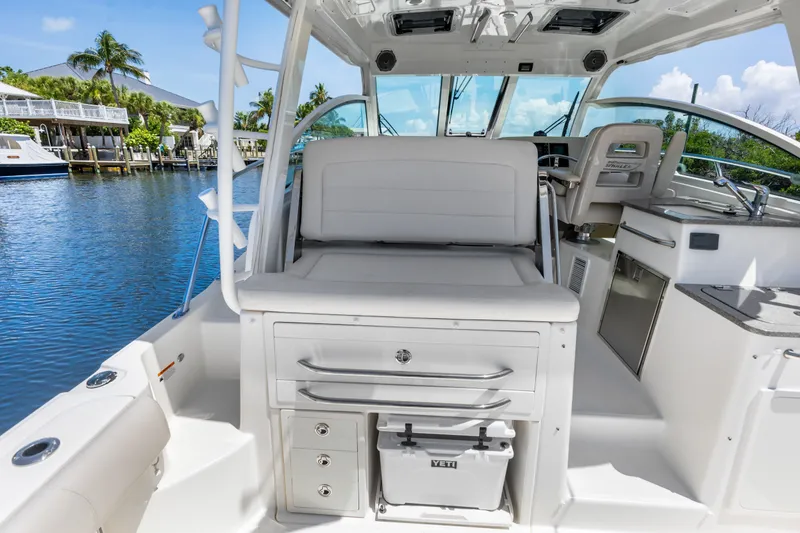 Slide: The Image of 2018 Boston Whaler 345 Conquest interior with seating, storage, and helm, docked by water. - 24