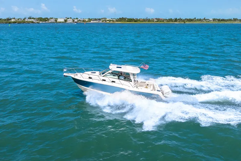 Slide: The Image of A 2018 Boston Whaler 345 Conquest speeds across blue waters, with a flag at the stern. - 2